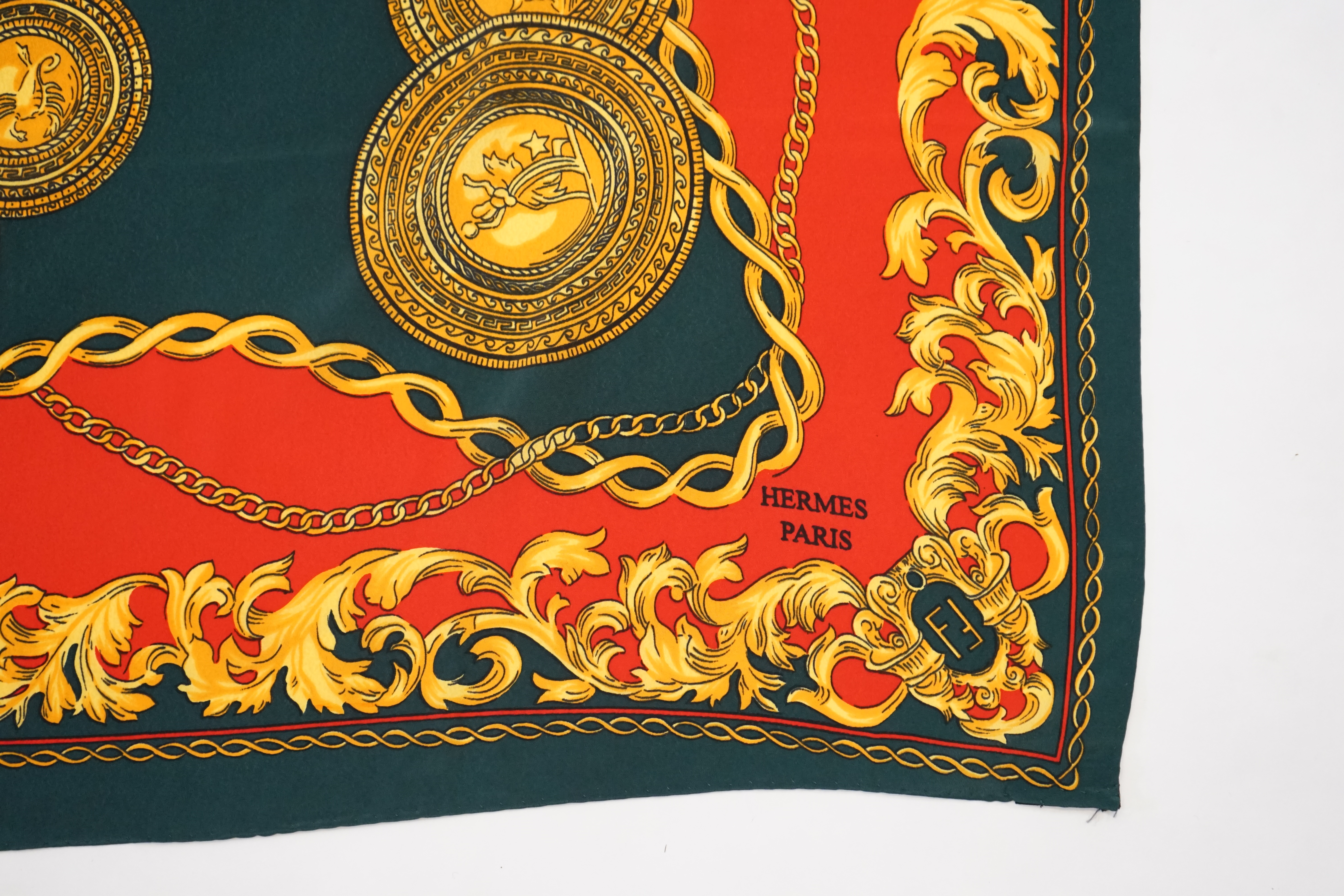 A Hermès silk scarf decorated with gold zodiac sign animals and hybrids, gold foliage and chain design around the edges, 90 x 84cm